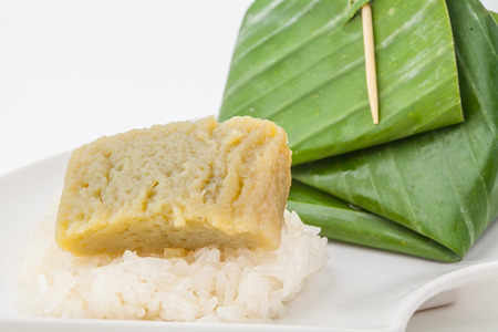 Thai dessert, Sticky rice with steamed custard, wrapped in banana on white paper backgroundの写真素材