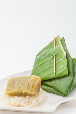 Thai dessert, Sticky rice with steamed custard, wrapped in banana on white paper backgroundの写真素材