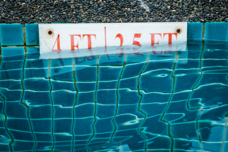 pool depth sign at the edge of the swimming pool