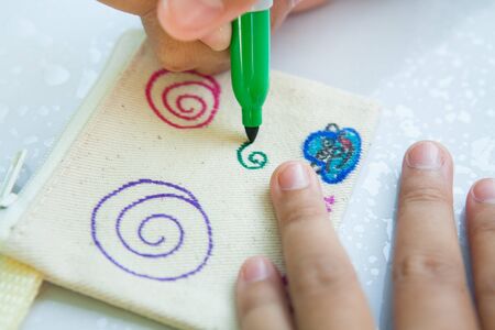 Child's hand painting on cloth with colorful pens.の写真素材