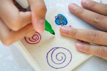 Child's hand painting on cloth with colorful pens.の写真素材