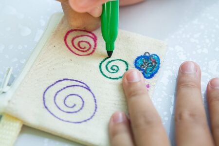 Child's hand painting on cloth with colorful pens.の写真素材