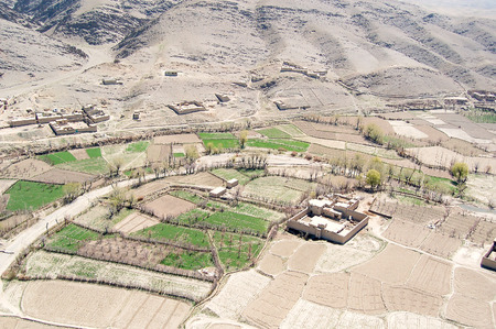 Aerial photo of a small village between Kabul and Ghazni in Afghanistan with green agricultural fields near a hillsideの写真素材