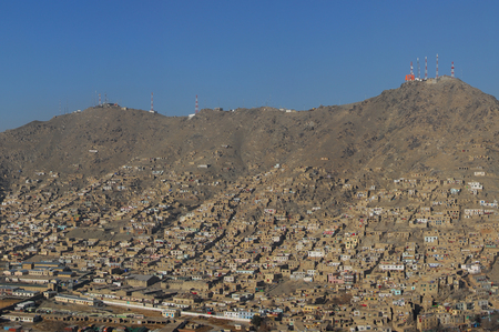 Aerial photo of an informal settlement on the hillside of Kabul in Afghanistan with transmission towers on top of the mountain in a distanceの写真素材