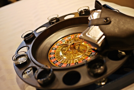 A close up photo of Roulette Drinking Game with shot glasses and blurred pistol grip. Bet and play the dangerous, exciting party game for adults only.の写真素材