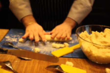 Blurred of Professional Italian Starred Chef in action: making pasta in a kitchen. Warm lighting....