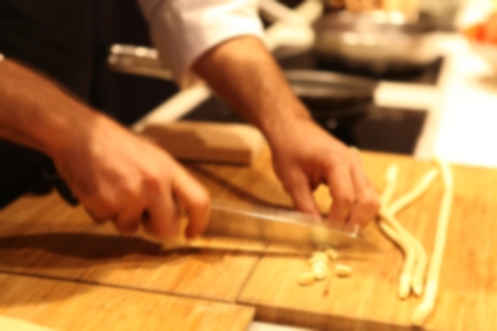 Blurred of Professional Italian Starred Chef in action: making and cutting pasta in a kitchen. Warm lighting. Blurred.の写真素材