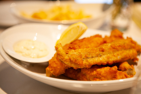Pile of piping hot and crispy delicious Fish and chips or fried battered fish and hot potato fries served with tartar sauce.の写真素材