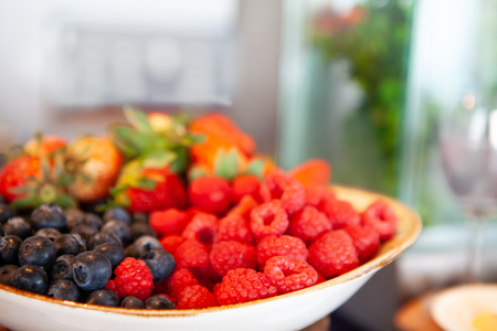Assortment of fresh, juicy and tasty fruit berries on white plate. Raspberry, blueberry and strawberry. Very nutritious and healthy food. Selective Focus. Natural light.の写真素材