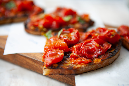 Delicious and colorful Bruschetta made with grilled cherry tomatoes on top of toasted bread rubbed...