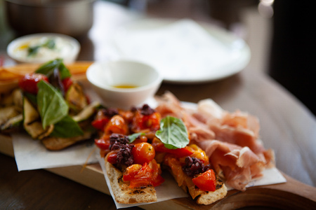 Delicious and colorful Bruschetta topped with grilled cherry tomatoes together with Prosciutto di...