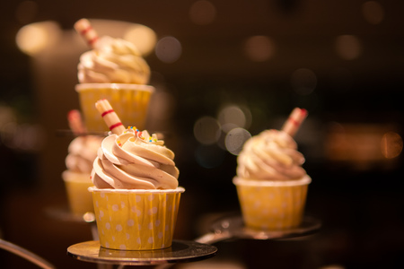 Tasty and delicious cupcake with decoration on a stand with bokeh lights background. perfect for romantic date night or celebrate birthday party. Elegant concept.の写真素材