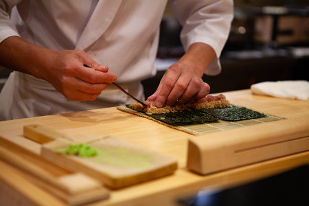 Professional and experienced sushi chef is focus and carefully make sushi with confident and dedication to perfection. Precision and Finesse at its best practice to achieve top performance in businessの写真素材