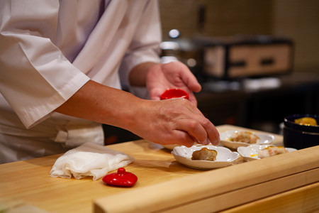 Professional and experienced sushi chef carefully add final touch with confident and dedication to his perfect sushi. Precision and Finesse at its best practice to achieve top performance in business.の写真素材