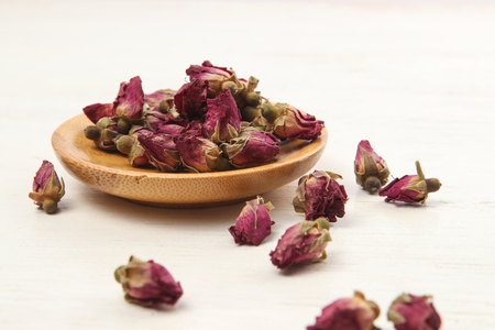 Rose tea in a cup with rose bud on wooden tableの写真素材