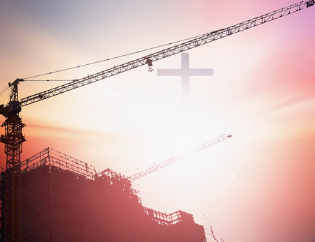 Industrial construction cranes and building silhouettes over sun at sunriseの写真素材