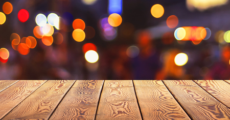 Christmas concept: Festive background with light spots and bokeh in front of a empty wooden tableの写真素材
