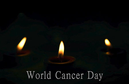 World Cancer Day concept: the candles burn brightly on the dark backgroundの写真素材
