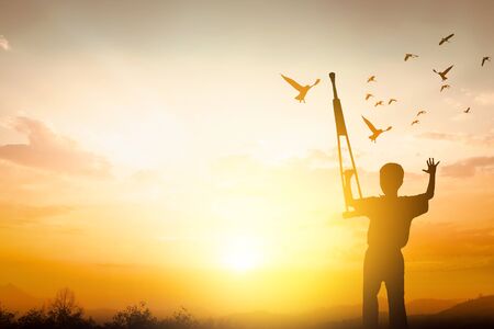 International Day of Peace concept, disabled person with crutches silhouette at sunset backgroundの写真素材