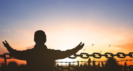 China Closed city concept: Silhouette refugee hands raising and barbed wire on sunset sky backgroundの写真素材