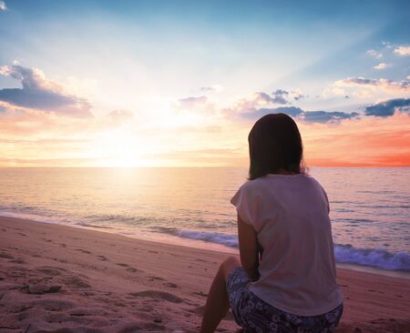International Women's Day concept: woman looking at the sea during the sunset on the beachの写真素材