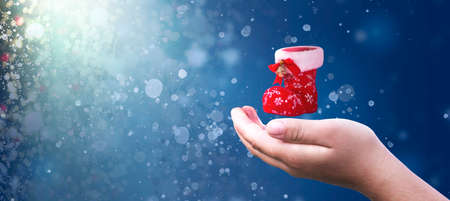 Christmas concept: hand hold Christmas shoes on Abstract christmas lights background