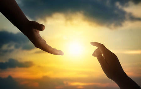 Rescue concept: Silhouettes of hands reaching out for hope and supporting each other on sunset background.の写真素材