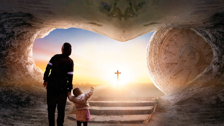 Easter and Good Friday concept, Mom and child standing with empty tomb of Jesus Christ at cross on sunset backgroundの写真素材