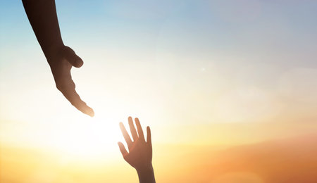 Hand reaching out to help someone on sunset sky background.の写真素材
