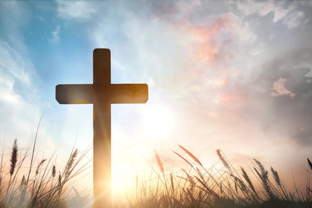 The cross on grass with sunset in the sky backgroundの写真素材