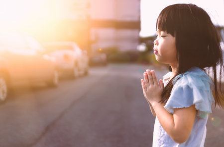 Little asian girl hand praying in morning sunrise light.の写真素材