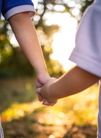 Two children hold hands in the natural outdoor background of sunsetの写真素材