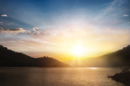 Scenic view of beautiful sunset or sunrise above the pond or lake at spring or early summer evening with cloudy sky backgroundの写真素材