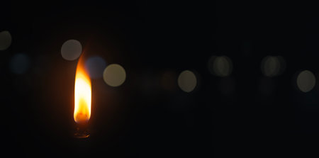 Burning candle on a black background with bokeh effect.の写真素材