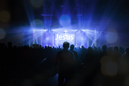 Worship includes music and numerous people lifting their hands in praise to God on stageの写真素材