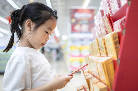 Little asian child girl using mobile phone in supermarketの写真素材