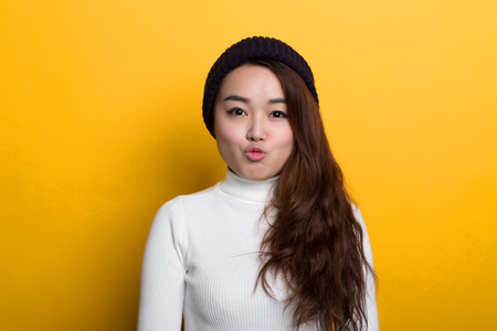 Young Chinese girl, various expressions on a yellow backgroundの写真素材