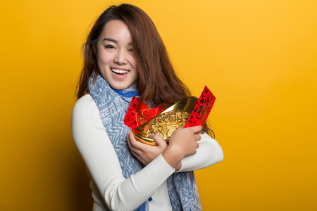 Yellow background, Chinese girl holding gold and blessing bag, Asian custom figure seriesの写真素材