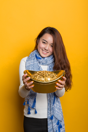 Yellow background, Chinese girl holding gold and blessing bag, Asian custom figure seriesの写真素材