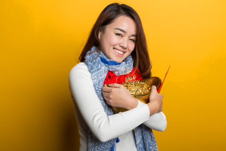 Yellow background, Chinese girl holding gold and blessing bag, Asian custom figure seriesの写真素材