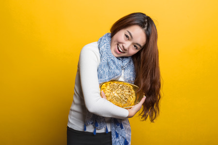 Yellow background, Chinese girl holding gold and blessing bag, Asian custom figure seriesの写真素材