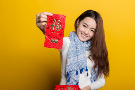 Yellow background, Chinese girl holding red Fu Bags, Asian custom characters picture seriesの写真素材