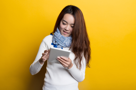 Young Chinese girl using cell phone on a yellow backgroundの写真素材
