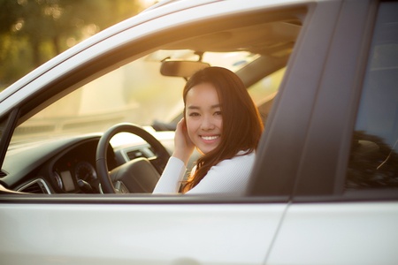 Charming Chinese girl driving a car, smiling toward the destinationの写真素材
