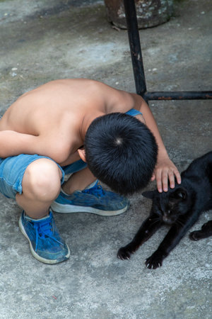Little boy petting black cat at homeの写真素材