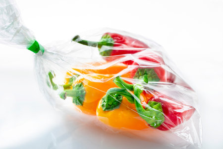 Sack of red and yellow fresh bell peppers on a white background
