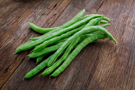 Fresh green vegetables beans with carrots on log tabletop