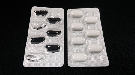 white pills in and out of panel on black backgroundの写真素材