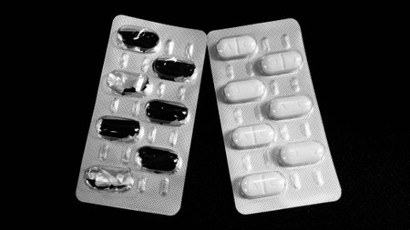 white pills in and out of panel on black backgroundの写真素材
