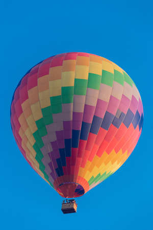 Colorful hot air balloon flying in the bright blue skyの写真素材
